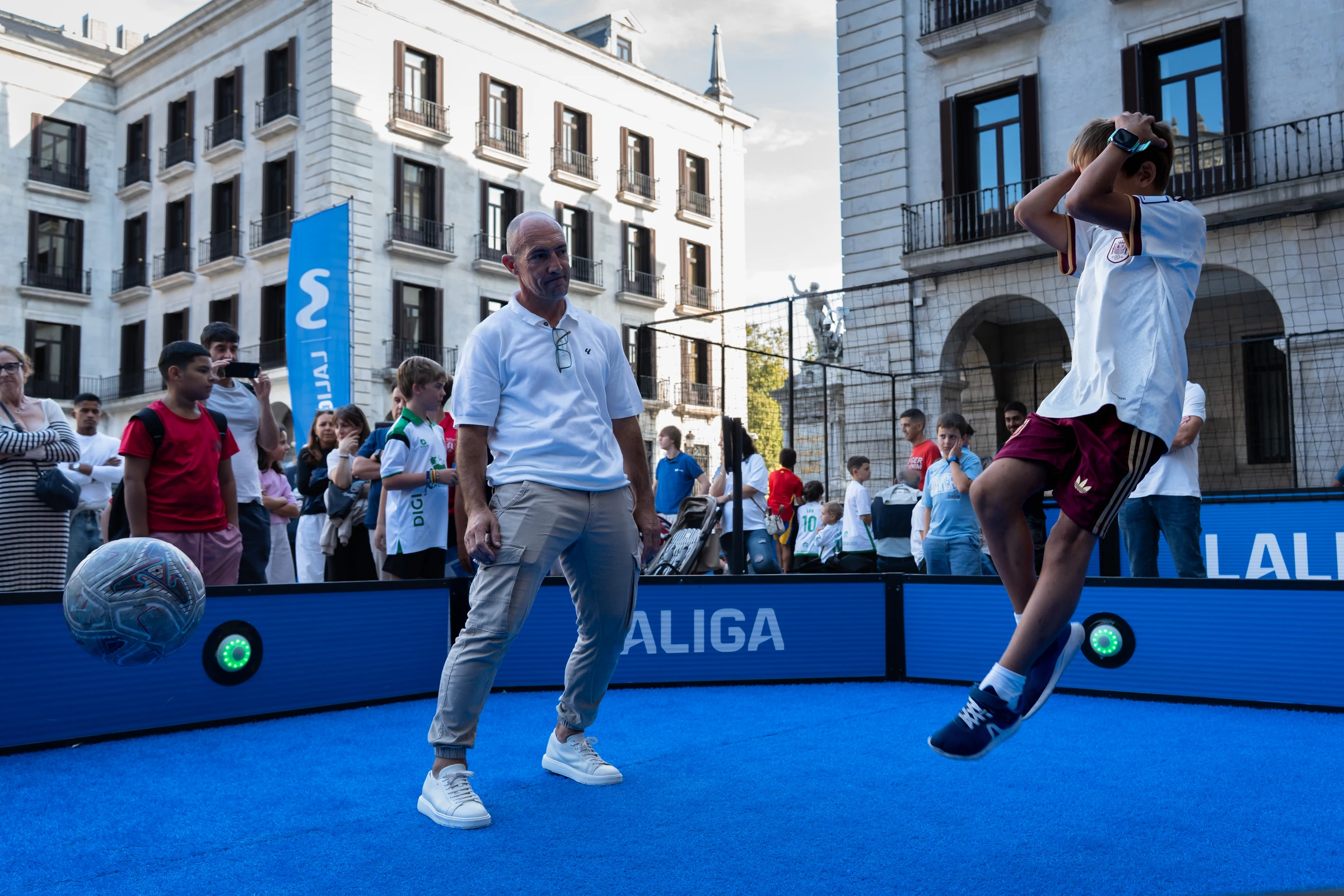 Un joven salta para golpear el balón junto a Pedro Munitis en la fan zone de Santander.