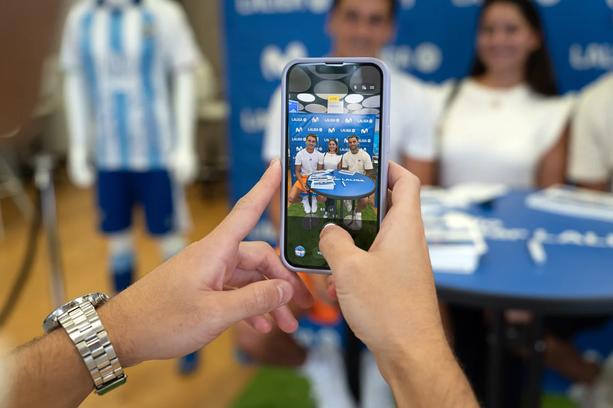 Un aficionado fotografía con su móvil a los jugadores del Málaga en la tienda Movistar.